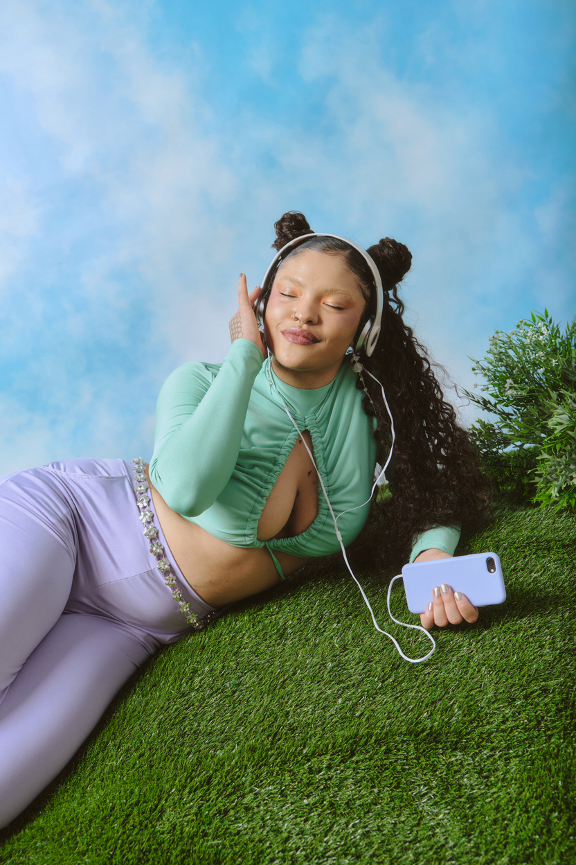 Stylish Woman Lying on Grass and Listening to Music